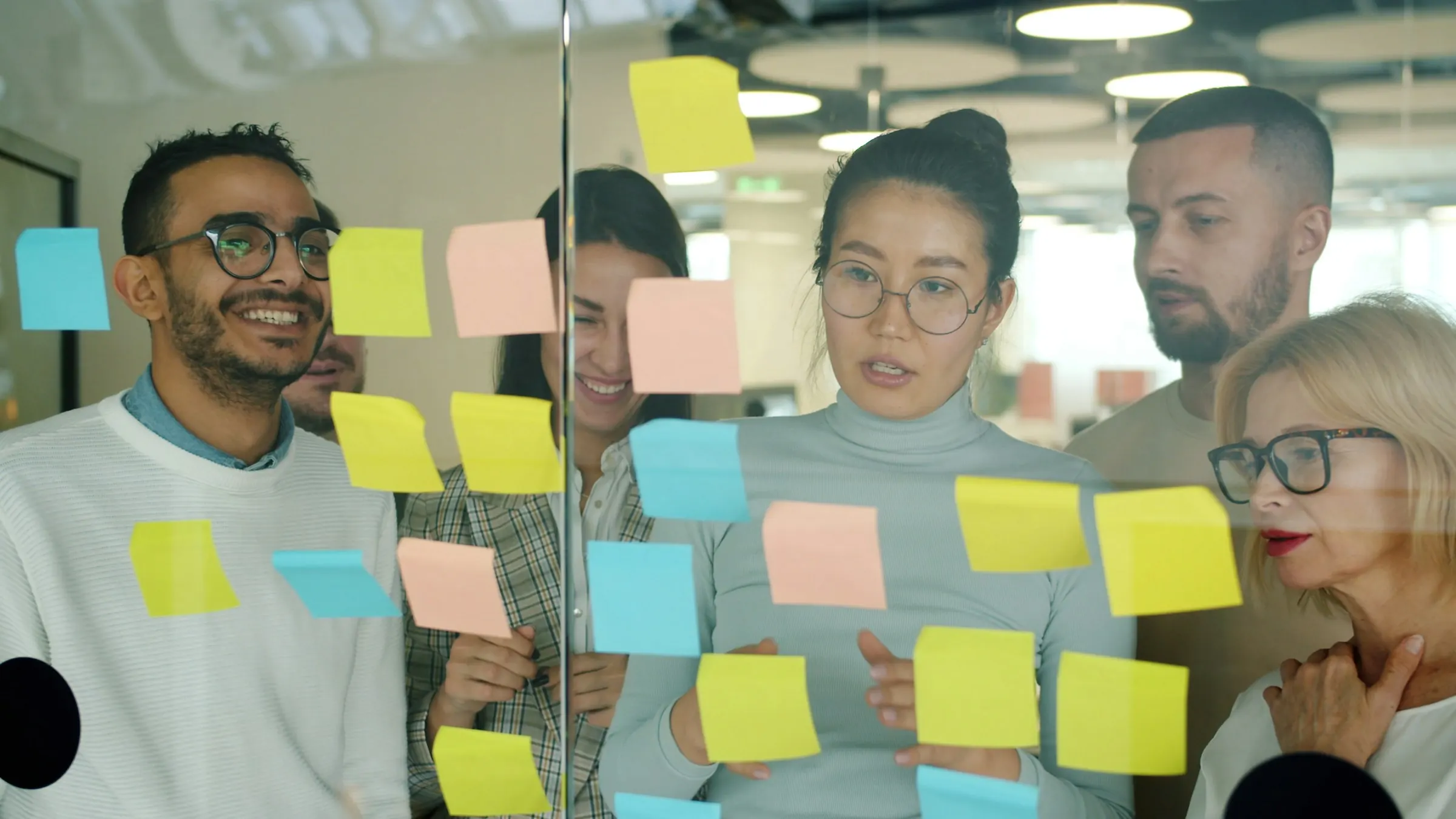 A creative team brainstorming with sticky notes on a glass wall